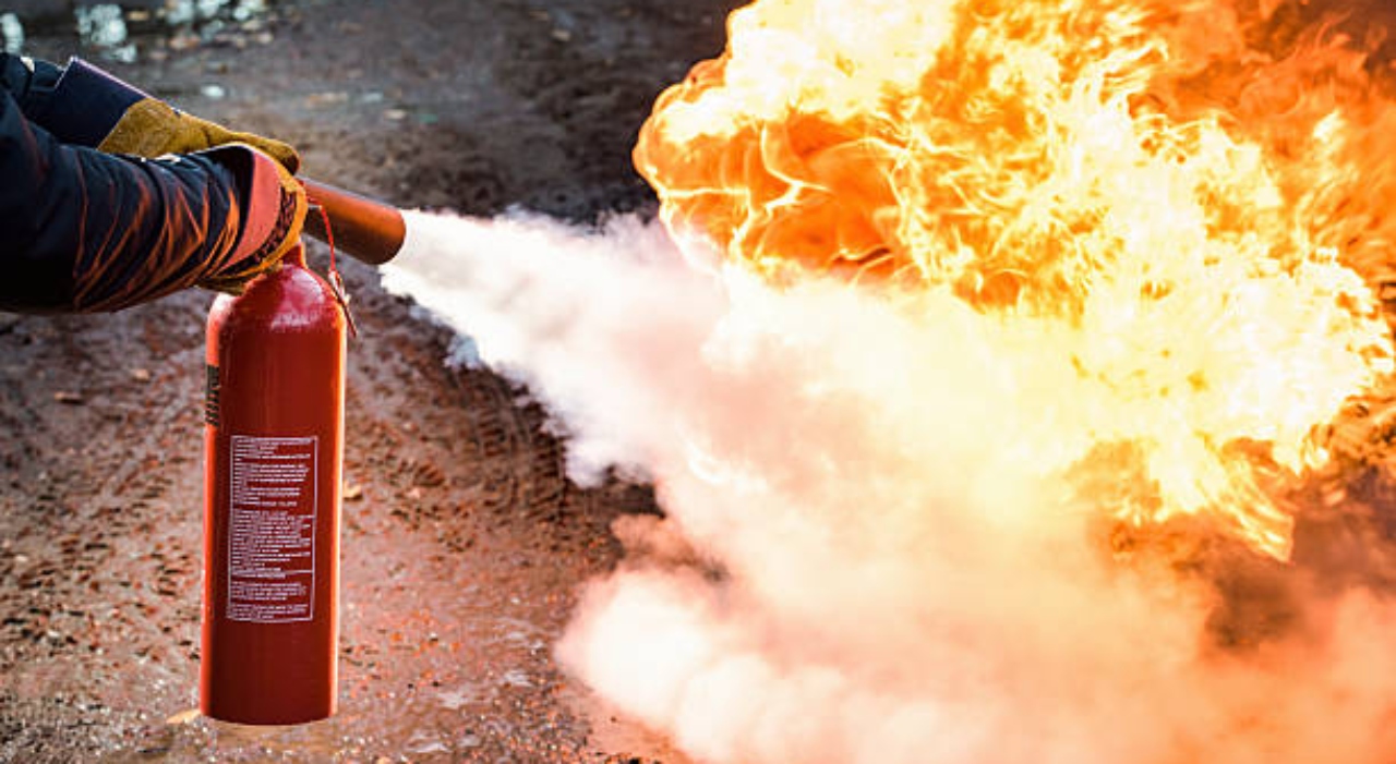 A man using a carbon dioxide fire extinguisher to fight a fire